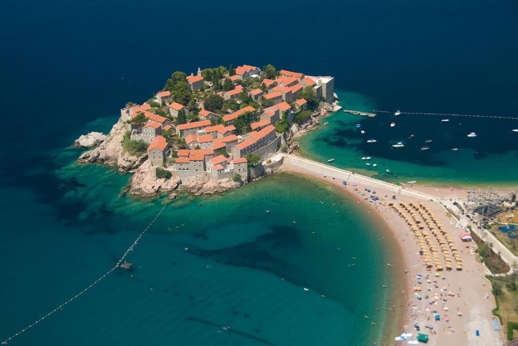 an island in the water with a house on it at Apartmani More in Sveti Stefan