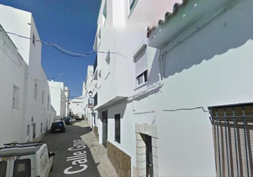 un callejón con edificios blancos y un coche en una calle en Estudio en el centro de Conil, en Conil de la Frontera