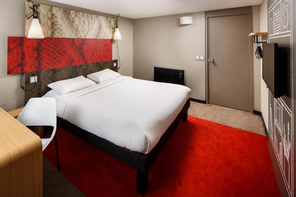 - une chambre avec un grand lit blanc et un tapis rouge dans l'établissement ibis Coventry South, à Coventry