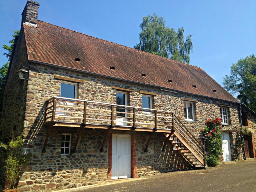 an old stone house with a wooden deck on it at Gîte du Moulin du Vey in Clécy