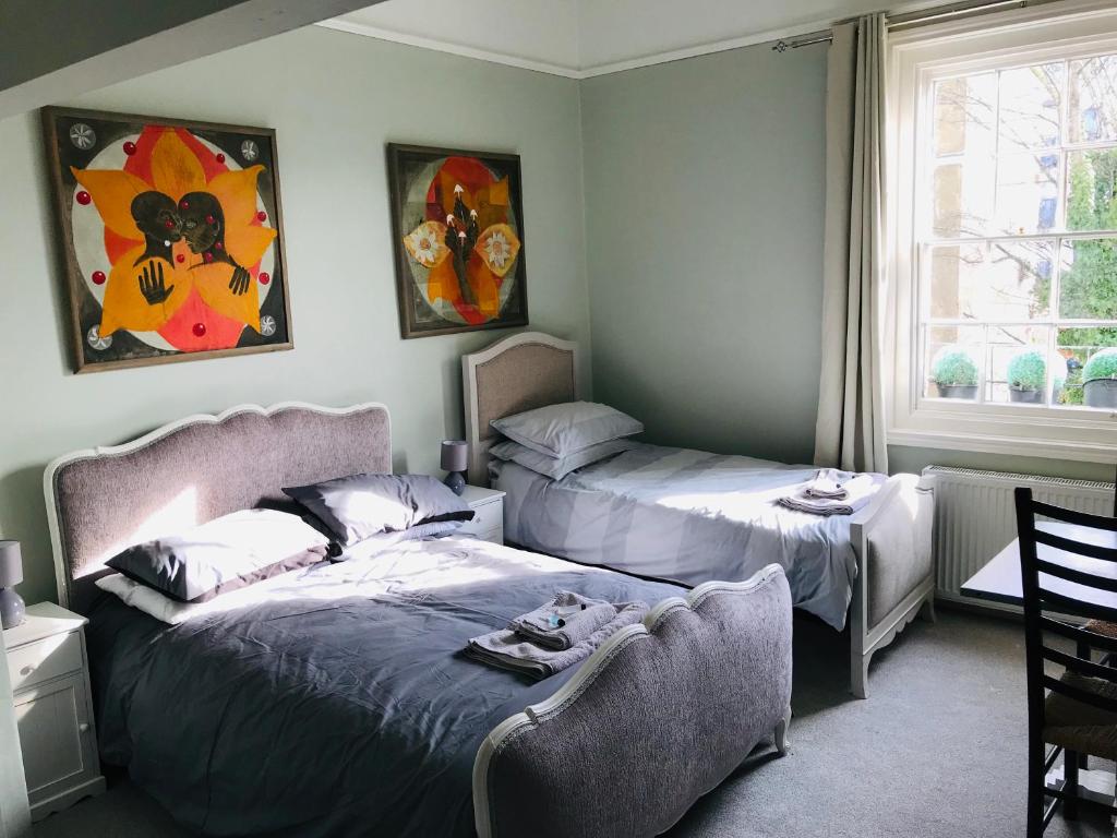 a bedroom with two beds and a chair and a window at Regency Rooms Guesthouse in Cheltenham