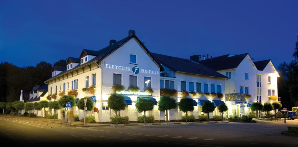 een groot wit gebouw met bomen ervoor bij Fletcher Landhotel Bosrijk Roermond in Roermond