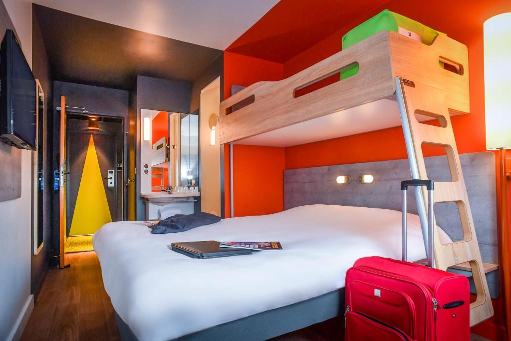 a bedroom with a bunk bed with a ladder and a suitcase at ibis budget Coutances in Coutances