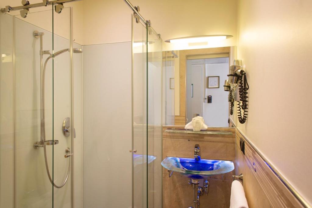 a bathroom with a glass shower and a sink at Hotel Deutsche Eiche in Munich