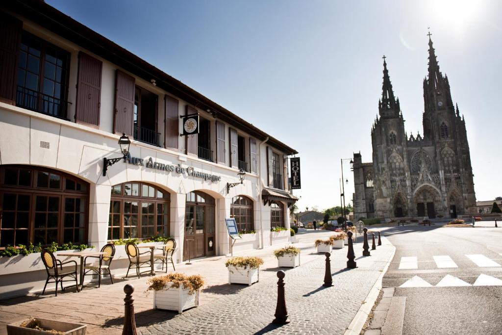 uma rua com um edifício com cadeiras e uma igreja em Armes de Champagne em Châlons-en-Champagne