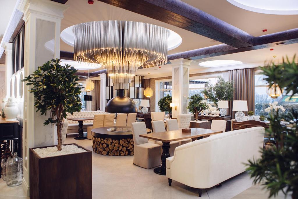 ein Restaurant mit einem großen Kronleuchter sowie Tischen und Stühlen in der Unterkunft Golden Horse Hotel in Taganrog