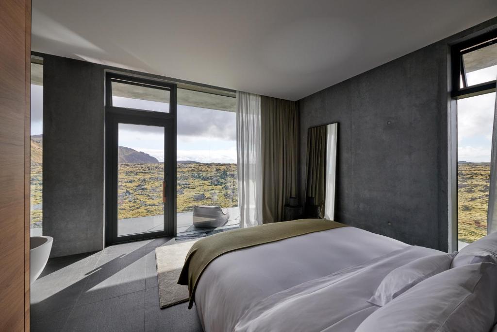 a bedroom with a large bed and large windows at The Retreat at Blue Lagoon Iceland in Grindavík