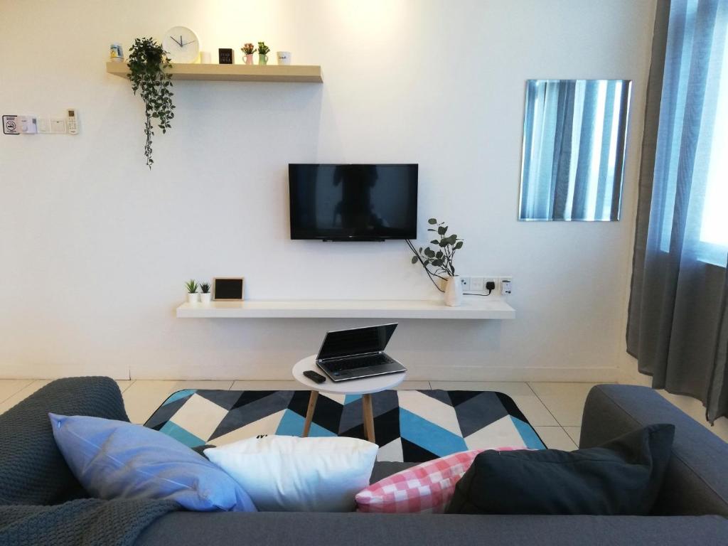 a living room with a couch and a tv on a wall at Puchong Skypod Residence, 1-4pax unit, Walking Distance to IOI Mall, 10min Drive to Sunway in Puchong