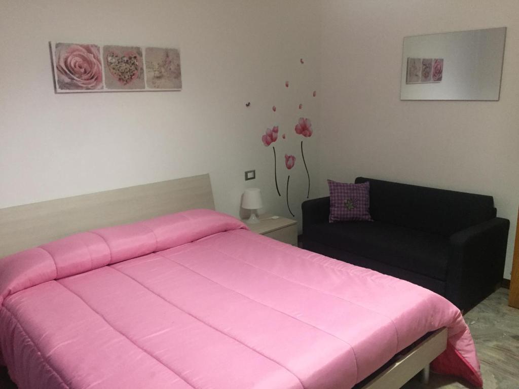 a bedroom with a pink bed and a black couch at App sul lungomare in San Benedetto del Tronto