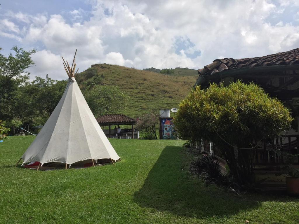 a teepee sitting in the grass next to a house at Ginebra Glamping in Ginebra