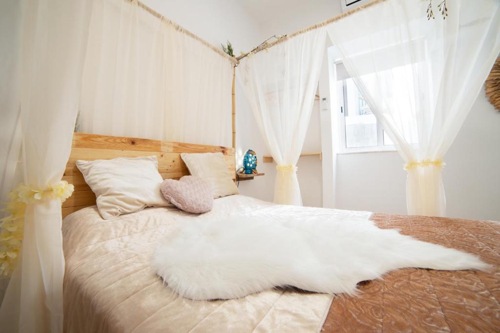 a bedroom with a white bed with white curtains at O Quintal Guesthouse in Carvoeiro