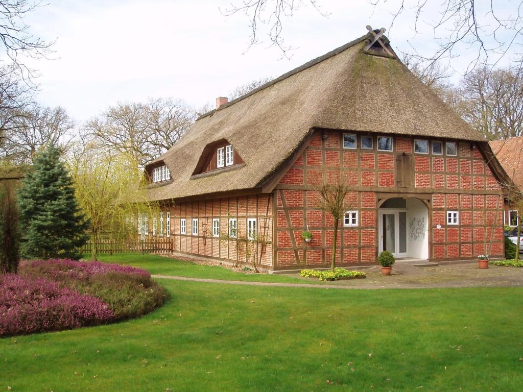 a large red brick house with a thatched roof at Davidshof, Bed & Breakfast in Schneverdingen