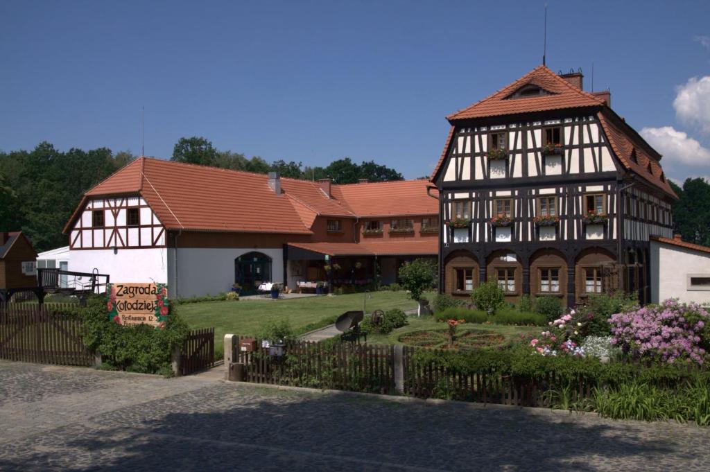 un grand bâtiment avec un jardin en face dans l'établissement Zagroda Kołodzieja, à Zgorzelec