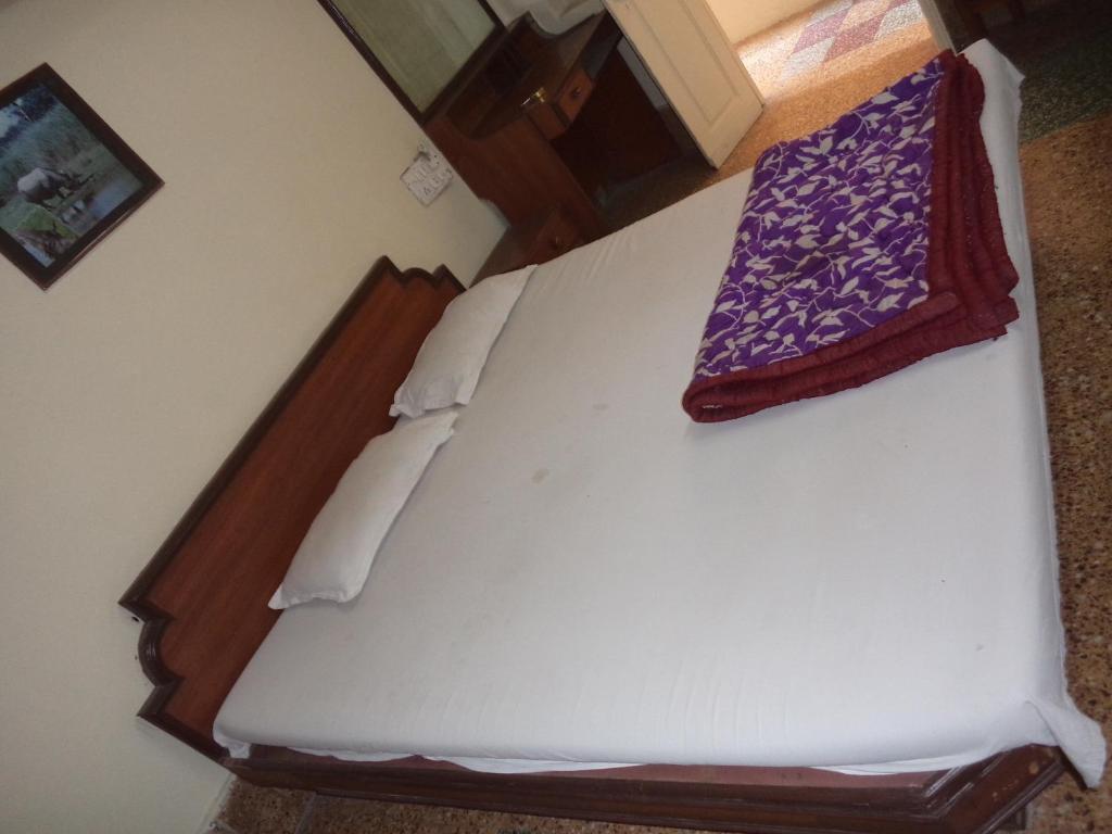 a white bed with a purple blanket on it at HOTEL NEELKAMAL in Indore