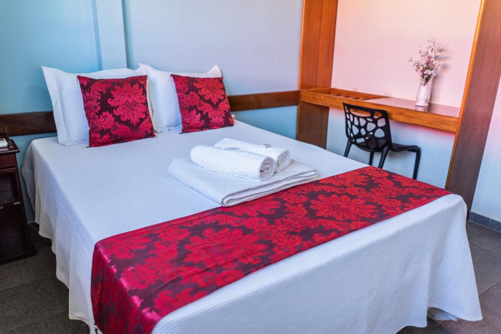 a bedroom with a white bed with red pillows at Pousada Paraiso in Guanambi