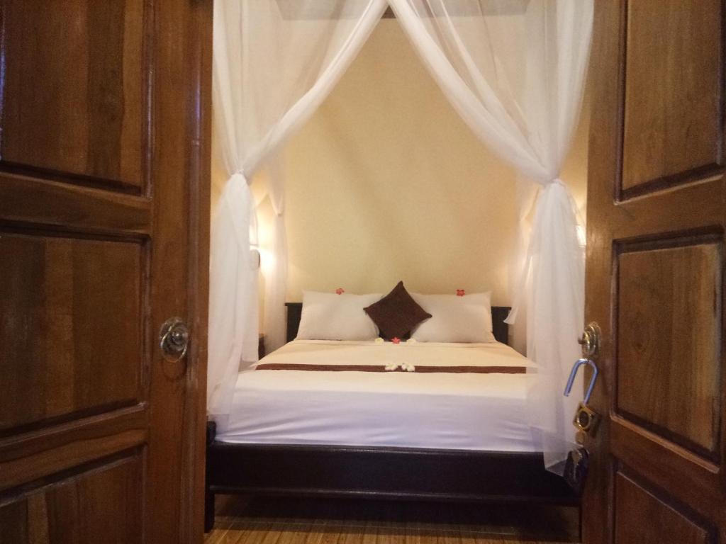 a bedroom with a canopy bed with white sheets and pillows at Molleh Guest House in Pemuteran