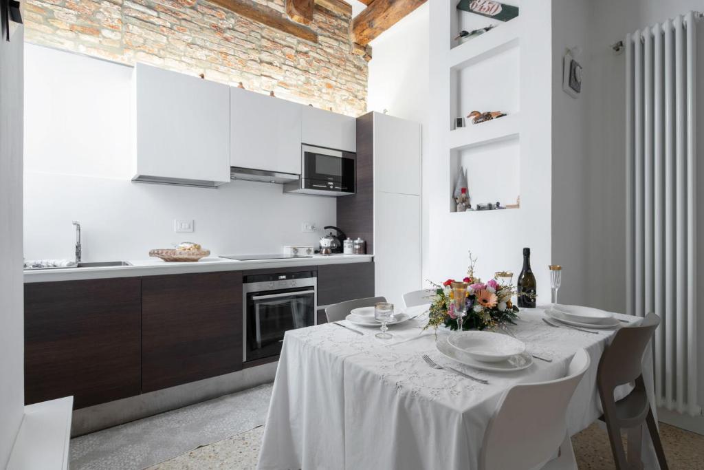 a white kitchen with a table with flowers on it at Ca' Flavia in Venice