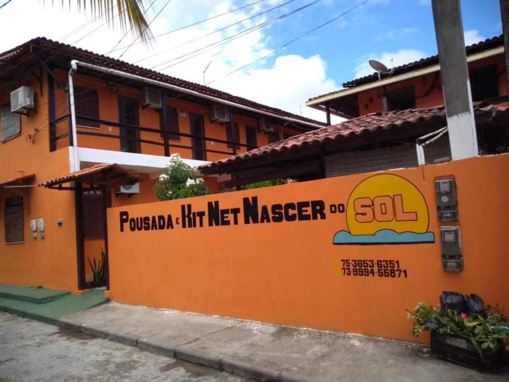 ein orangefarbenes Gebäude mit einem Schild an der Seite in der Unterkunft Pousada & Kitnet Nascer do Sol in Ilha de Boipeba