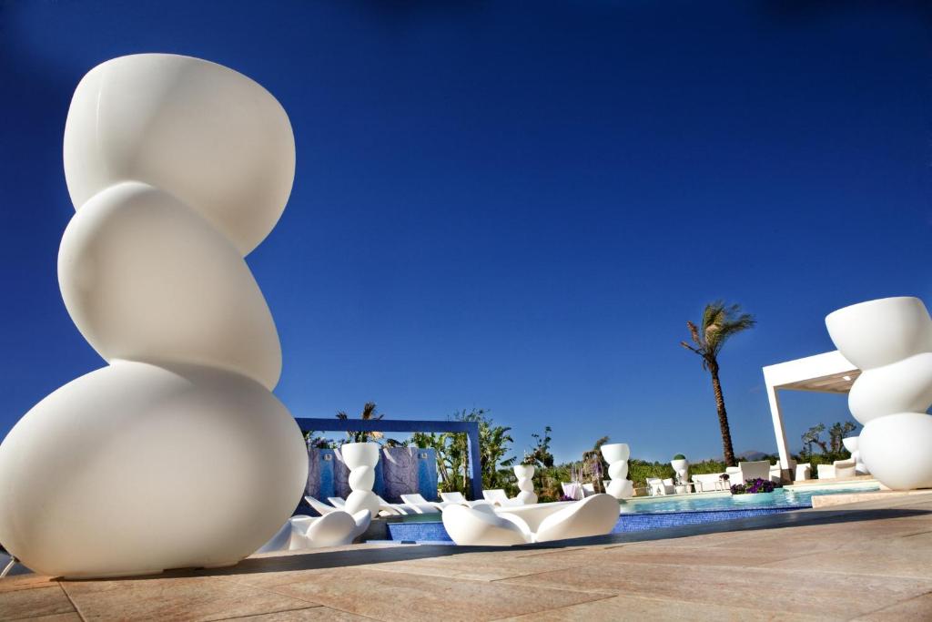 un gruppo di sculture bianche sedute accanto a una piscina di Borgo degli Angeli a Balestrate