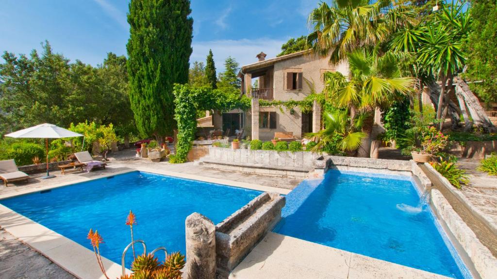 a swimming pool in front of a house at Finca GARROVERA Pollensa in Pollença