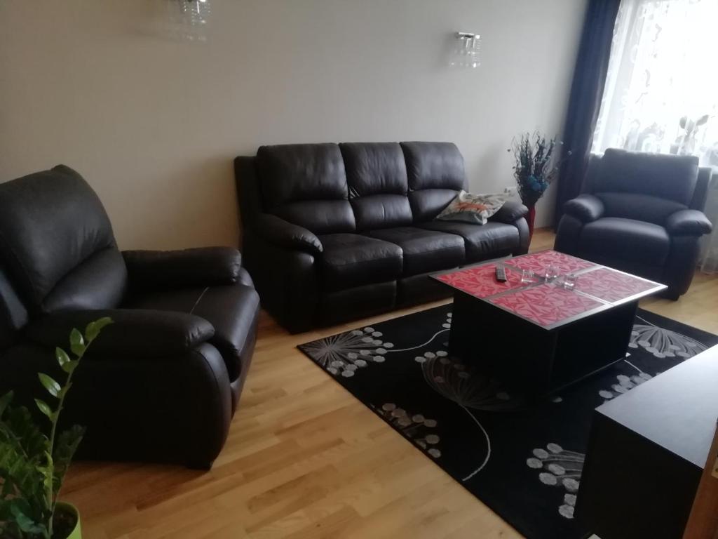 a living room with black leather furniture and a table at Justinos Apartamentai Panevėžyje in Panevėžys