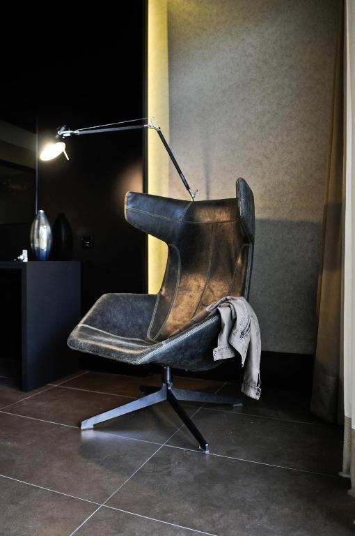 a leather chair sitting in a room with a lamp at Evidencia Belverde Hotel in Amora
