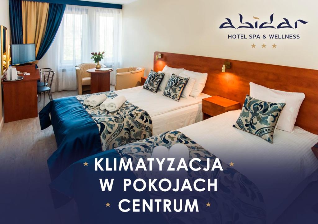 two beds in a hotel room with the words kimmel pokolniki at Abidar Hotel Spa & Wellness in Ciechocinek