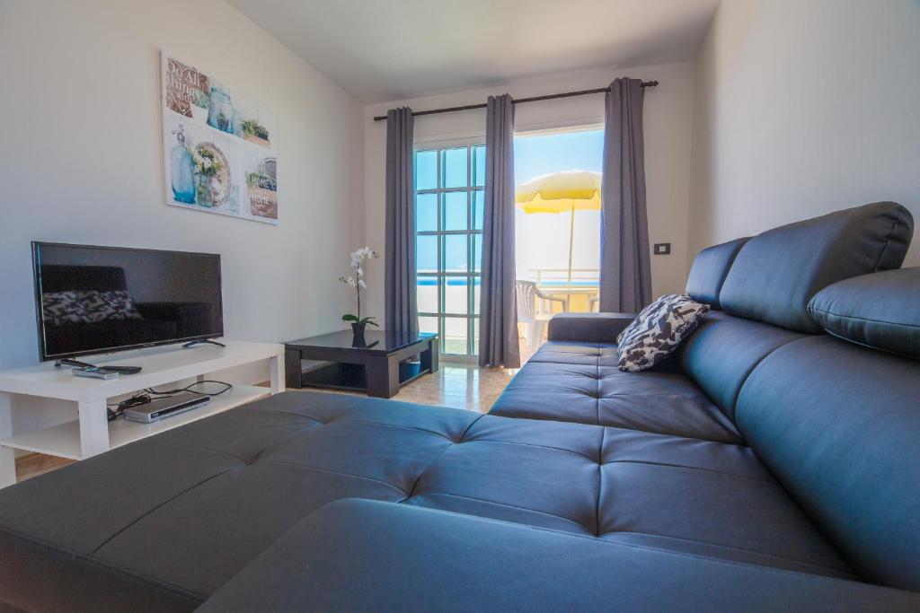 a living room with a blue couch and a television at Residencial Arena del Sol 6 by Olax Rentals in Puerto de Santiago