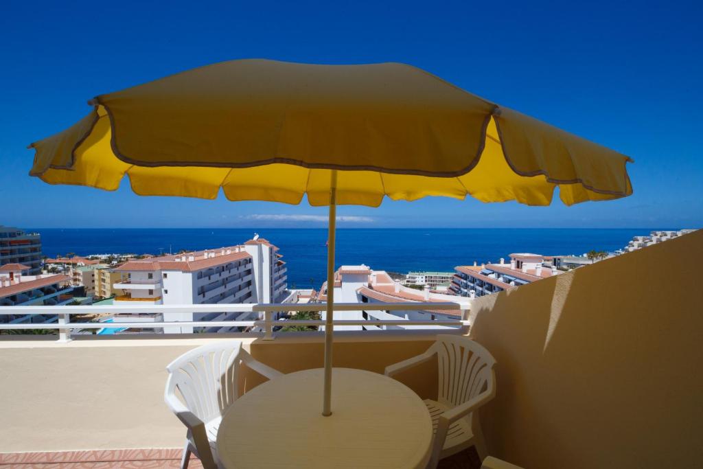 プエルト・デ・サンティアゴにあるArena del sol 6 FREE WIFIのバルコニーに黄色い傘付きのテーブル