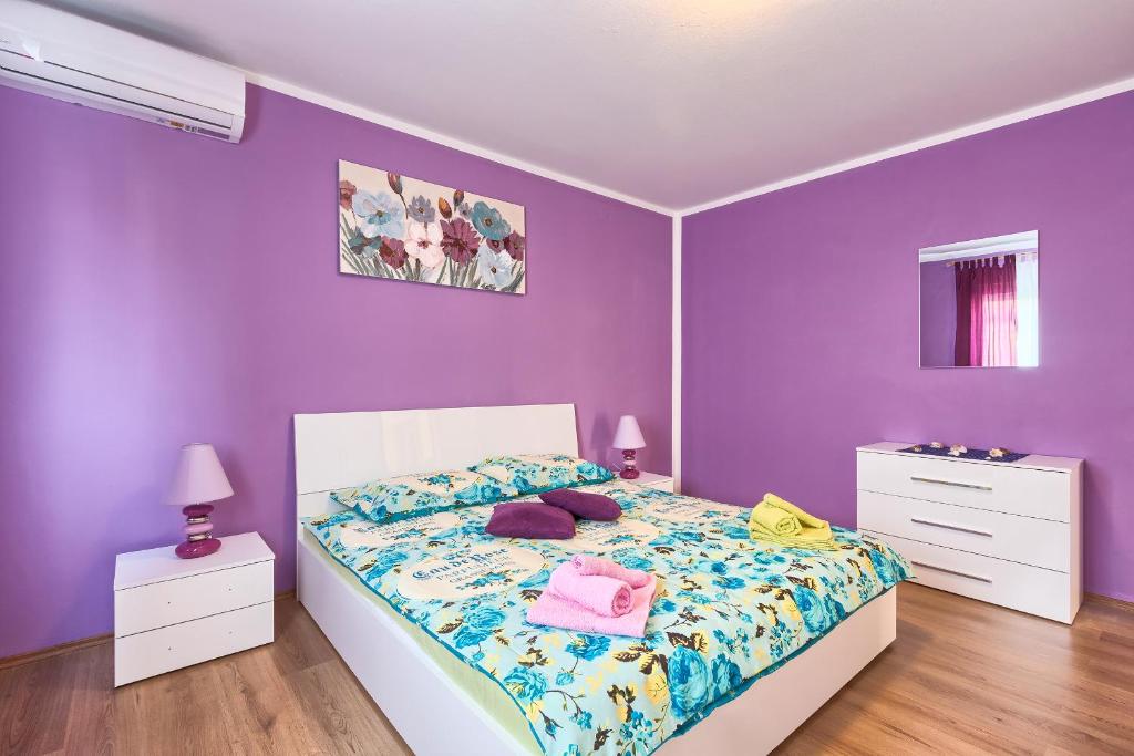 een slaapkamer met paarse muren en een bed met kussens bij Apartman Modry in Pula