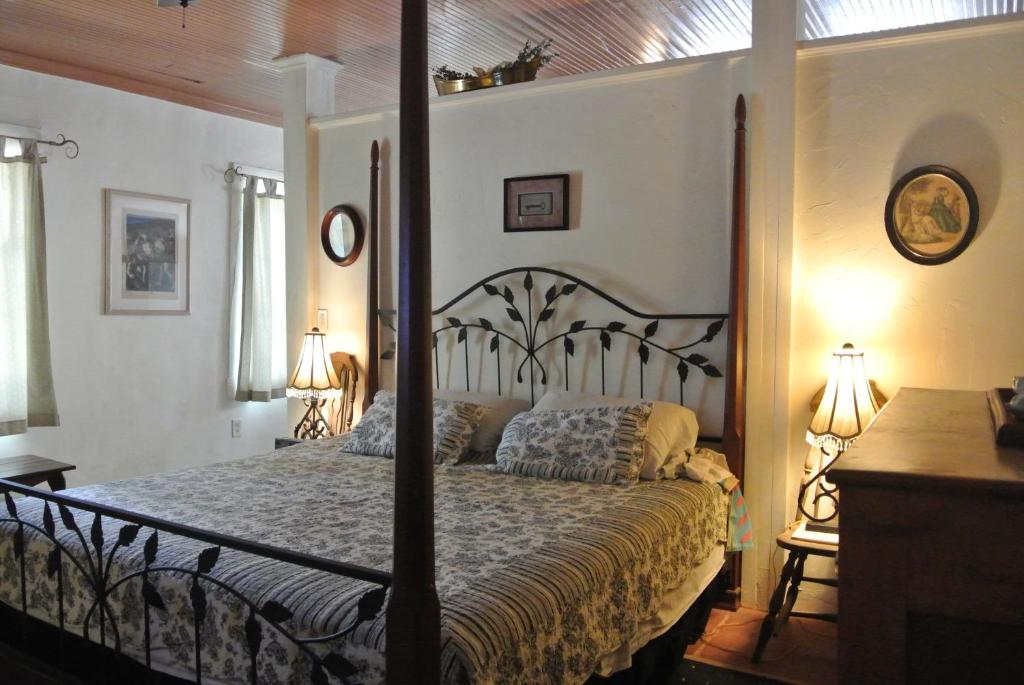 a bedroom with a four poster bed and two lamps at Inn at the L C Ranch in Gila