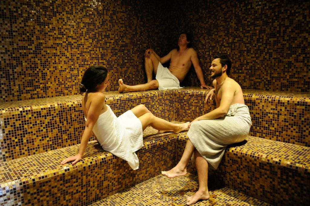 a group of three people sitting on a bench at Evidencia Belverde Hotel in Amora