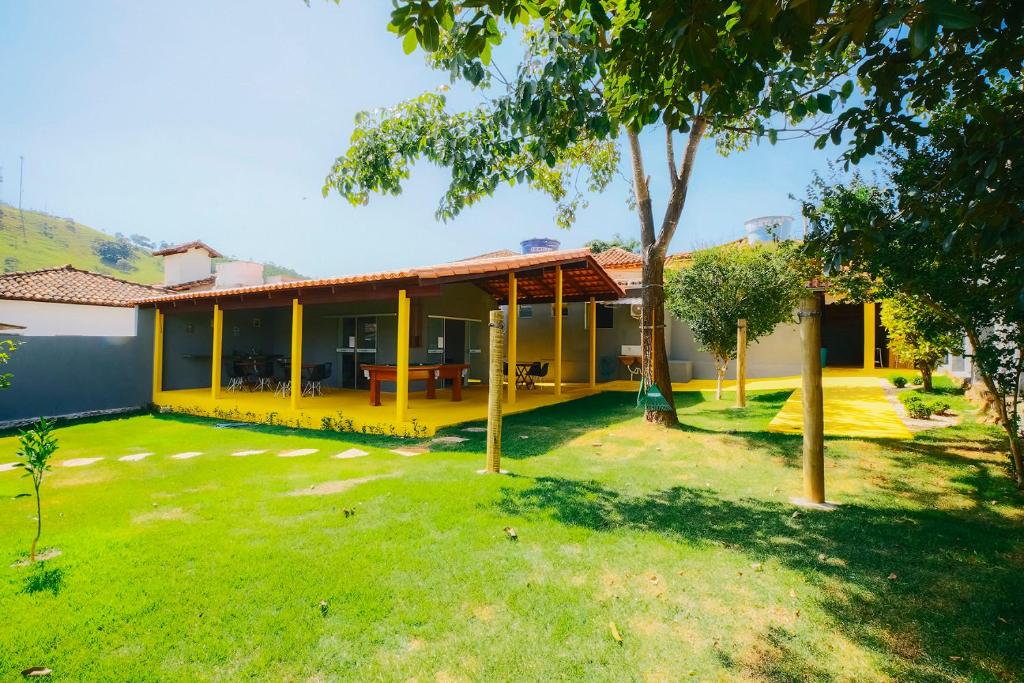 żółty dom z zielonym dziedzińcem w obiekcie Casarão Hostel w mieście Capitólio