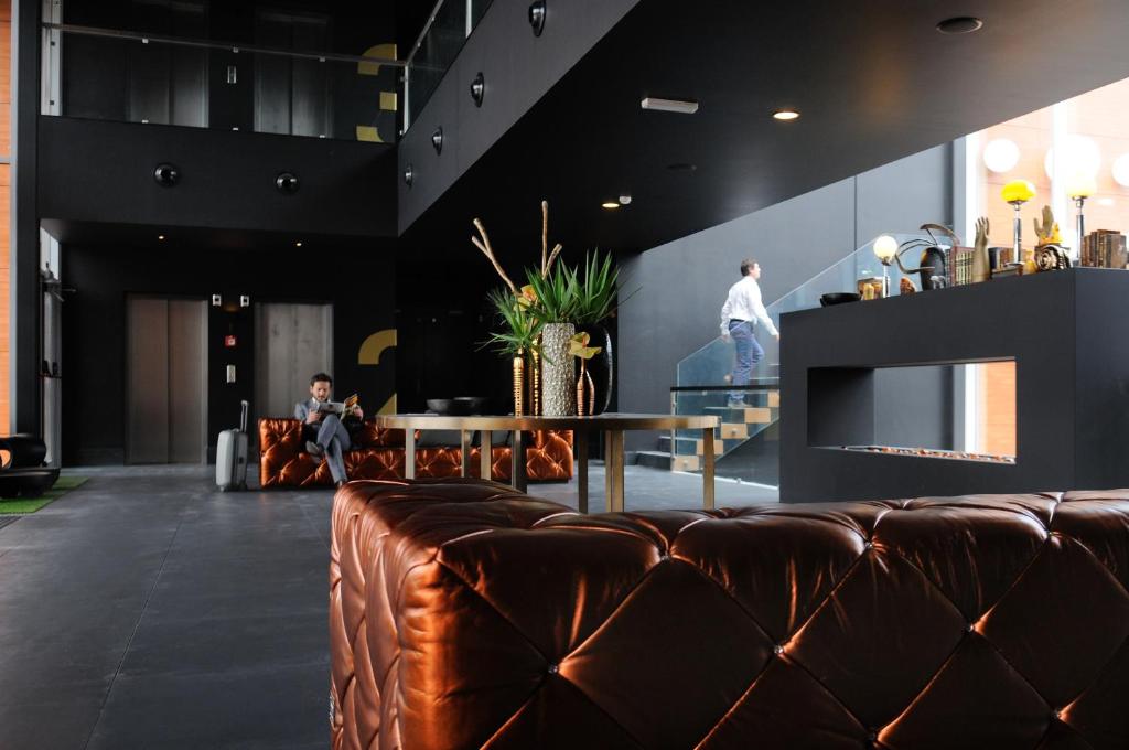 a lobby with a brown leather couch and a table at Evidencia Belverde Hotel in Amora