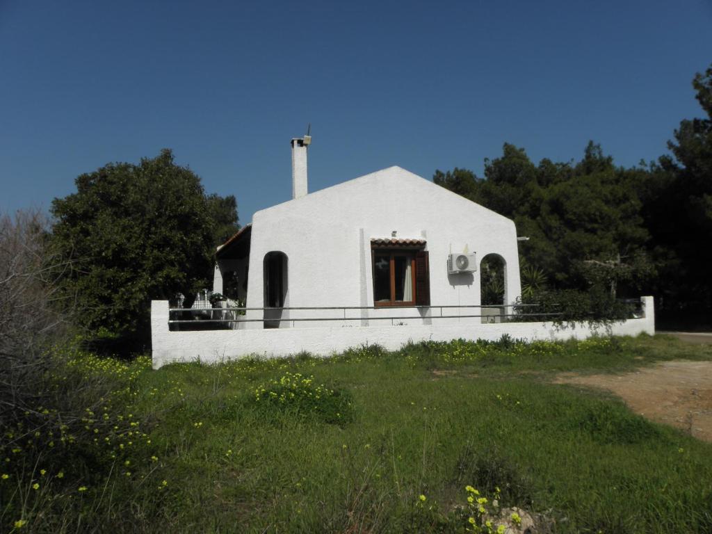 een kleine witte kerk met een kruis op een veld bij House By The Sea in Artemida