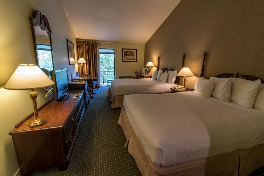 a hotel room with two beds and a desk with lamps at Interlaken Inn in Lakeville