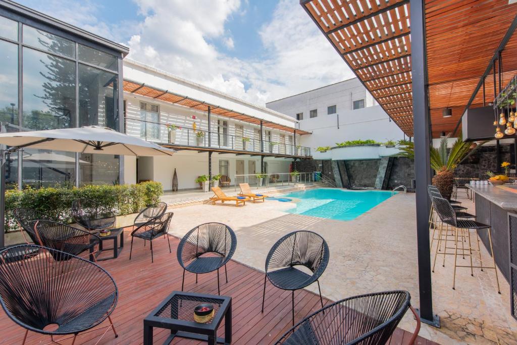 a patio with chairs and tables and a pool at Medellín Vibes Hostel in Medellín