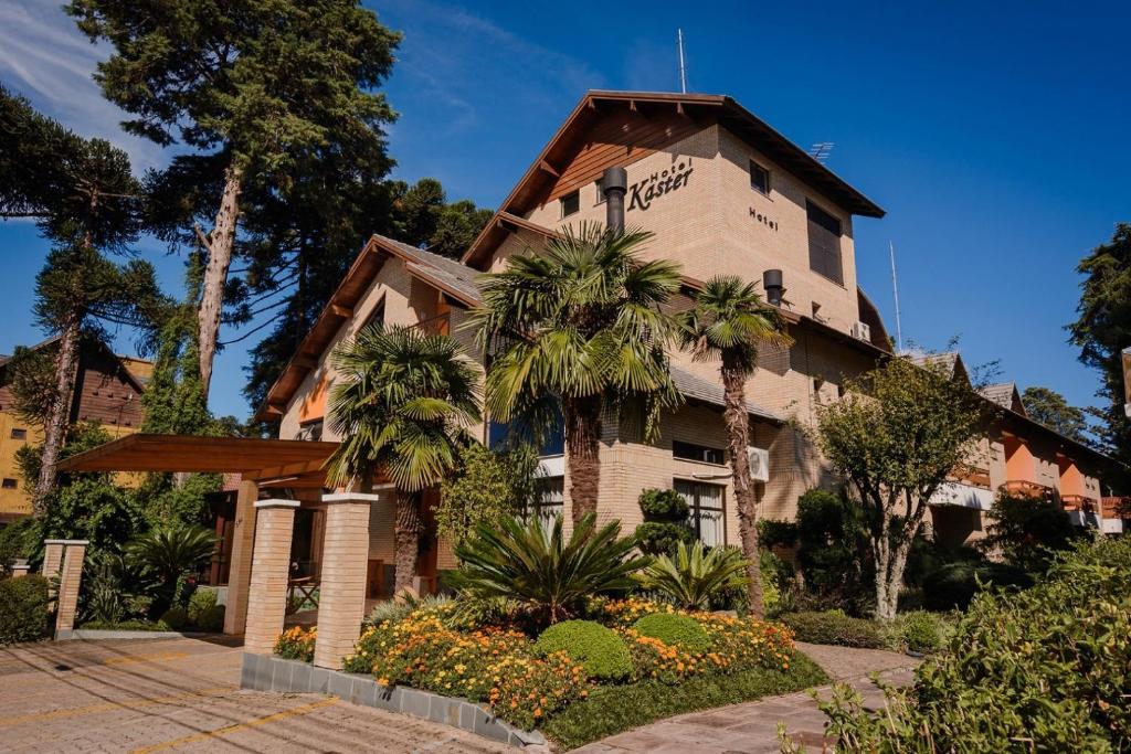 un edificio con palmeras delante en Hotel Pousada Kaster en Gramado