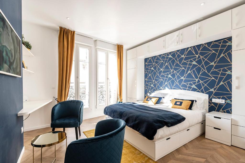 een slaapkamer met een bed met een blauwe accentmuur bij MM Suites Marlot in Reims