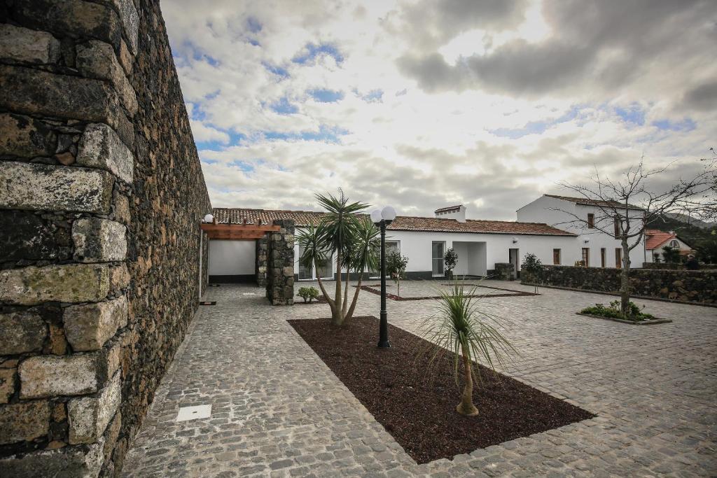 un edificio de piedra con palmeras en un patio en Quinta das Giestas, en Ribeira Grande