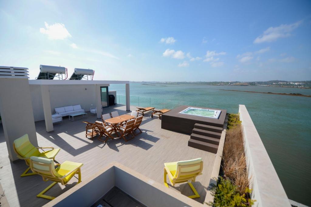 a balcony with chairs and a table and a view of the water at Arade Riverside Modern Apartment in Estômbar