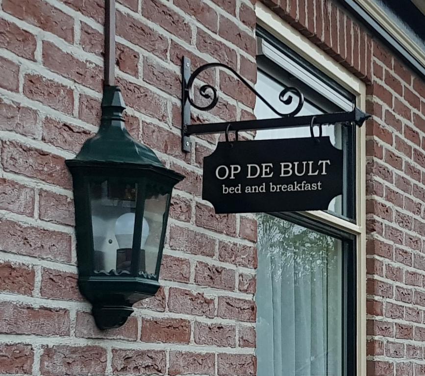 ein Straßenschild an einem Backsteingebäude mit Straßenbeleuchtung in der Unterkunft Op de Bult in Rasquert