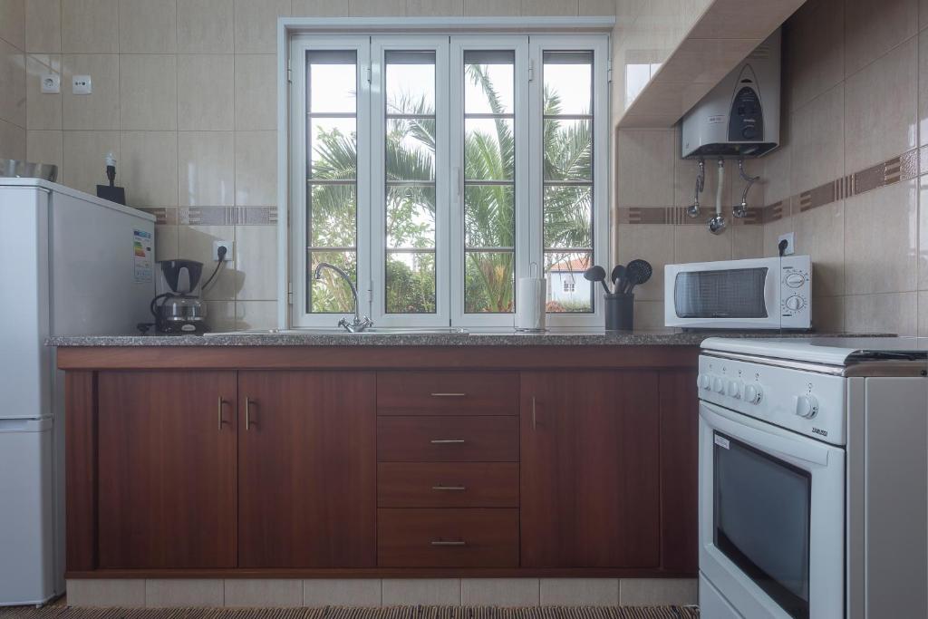 a kitchen with a sink and a microwave at Apartamentos em Casa da Avó Inês in Porto Formoso