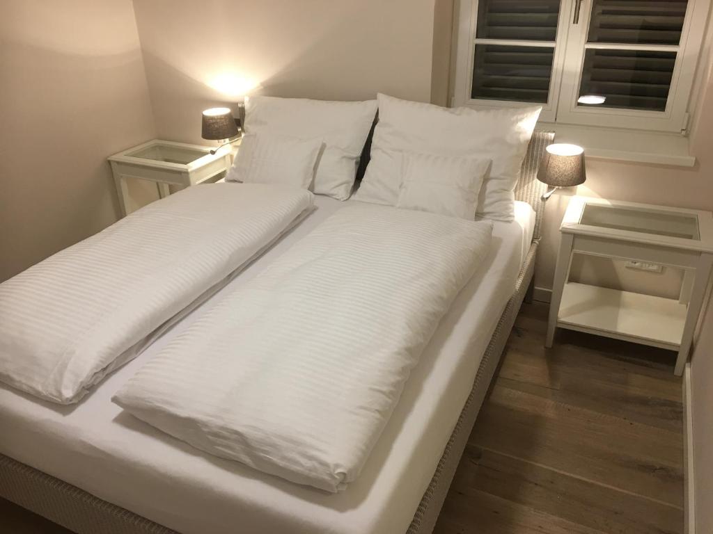 a large white bed with white sheets and pillows at Christmann's Cottage in Weisenheim am Berg