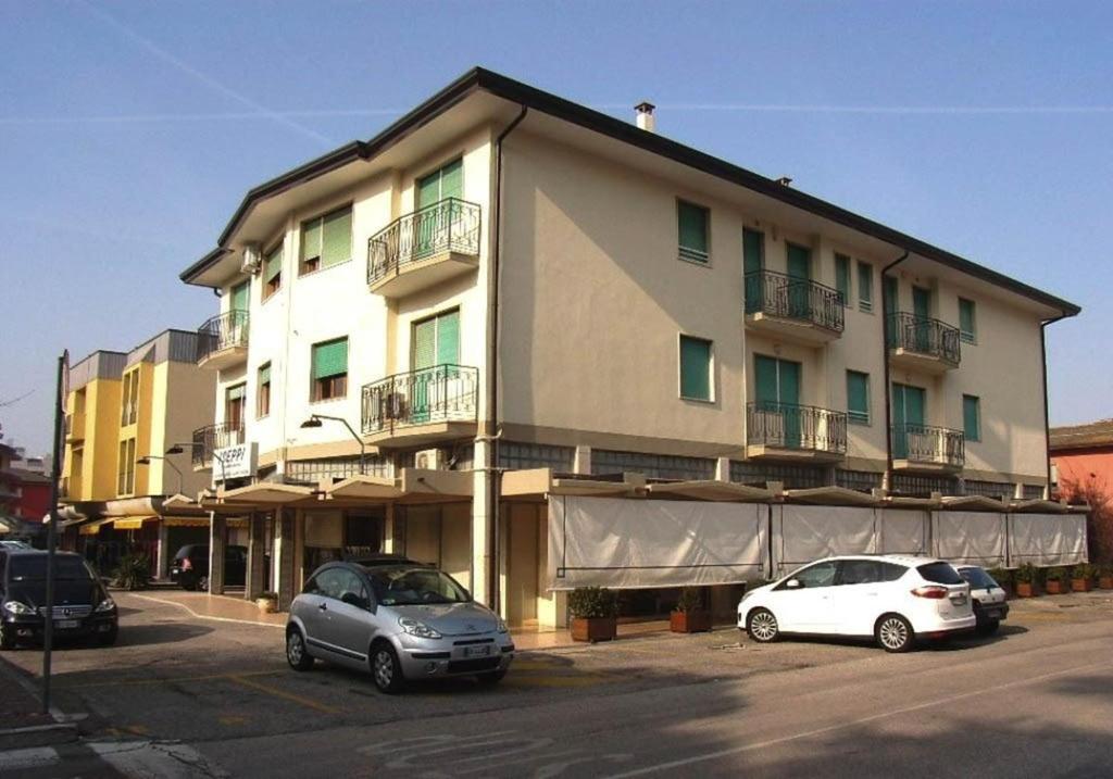 zwei Autos, die vor einem großen Gebäude geparkt sind in der Unterkunft Apartment in Eraclea Mare 25695 in Eraclea Mare