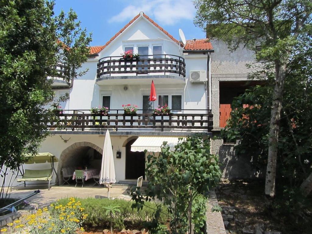 a white house with a balcony and an umbrella at Apartment in Marsici/Insel Krk 13109 in Sveti Vid-Miholjice