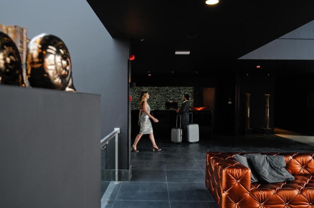 a woman walking down a hallway with a couch at Evidencia Belverde Hotel in Amora