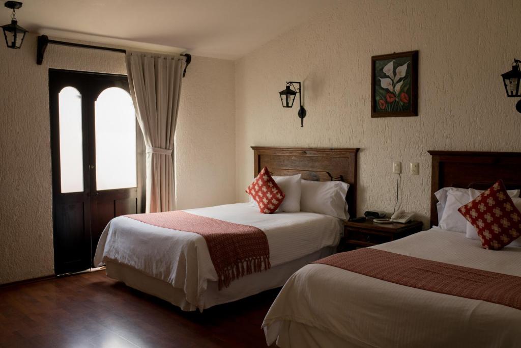 a hotel room with two beds and a window at Rosario Hotel in San Cristóbal de Las Casas