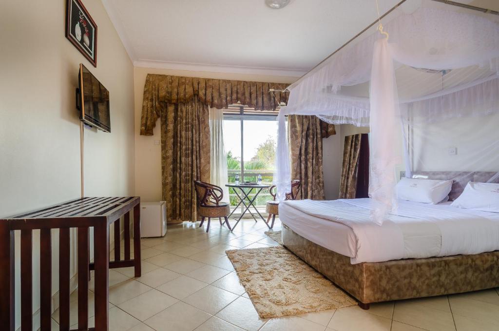 a bedroom with a canopy bed and a balcony at Victoria Travel Hotel in Kampala