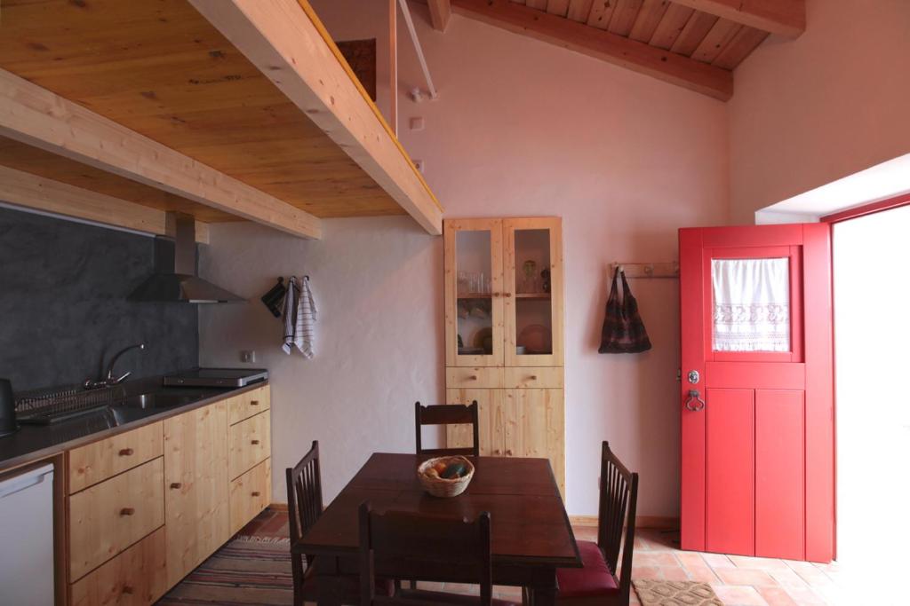 uma cozinha com uma mesa e uma porta vermelha em Casa das Minas em Minas de São Domingos